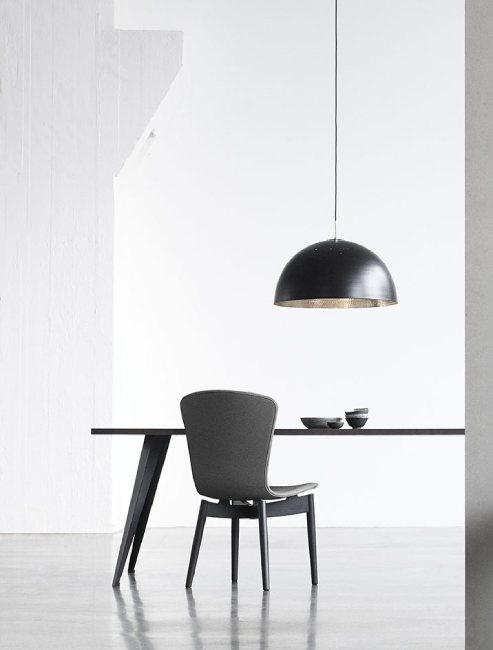 Space Copenhagen's Shade Light from Mater over a dining table in a minimalist space.