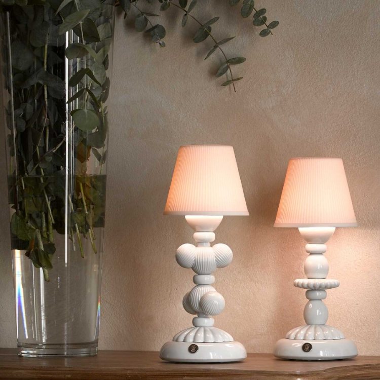 A Cactus Firefly portable table lamp and a Lotus Firefly portable table lamp sit on a credenza next to a vase of flowers.