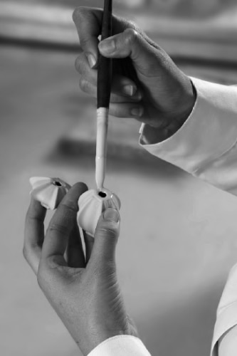 The hands of a Lladro artisan working with porcelain shapes. B&W.