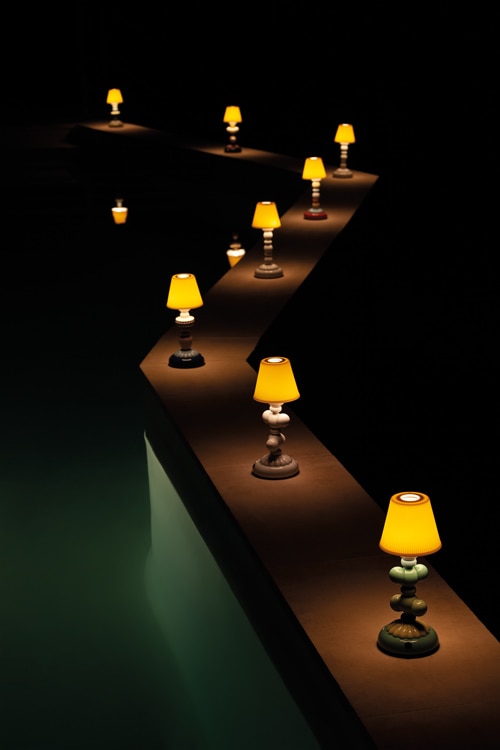 A dramatic shot of a line of Firefly portable table lamps illuminating a wall zig-zagging through the darkness.