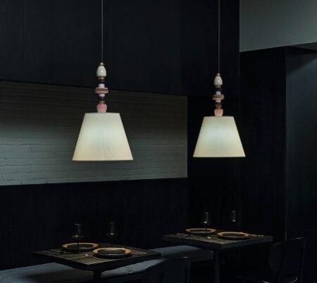 A pair of Firefly suspension lights from Lladro illuminate tables in an intimately dark restaurant.