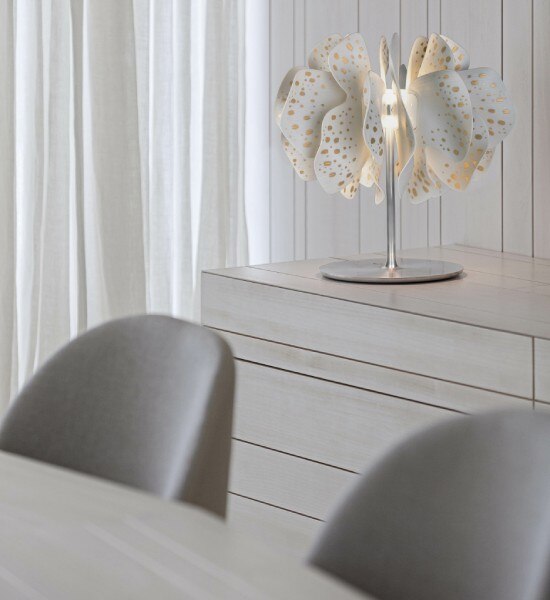 A gold-accented Nightbloom table lamp illuminates a sideboard in a contemporary dining room.