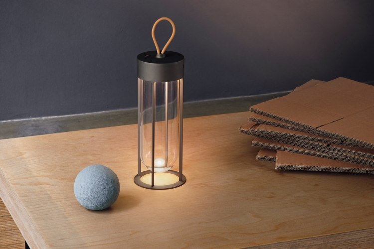 Philippe Starck's new In Vitro Unplugged portable table lamp for Flos sits on a wooden desktop.