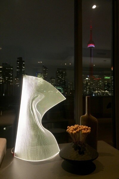 Gweilo Qin floor light sitting on a side table in a luxurious condo looking out over the Toronto skyline.