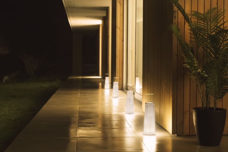 A line of Hipatia outdoor table lights on the veranda of an elegant modern home