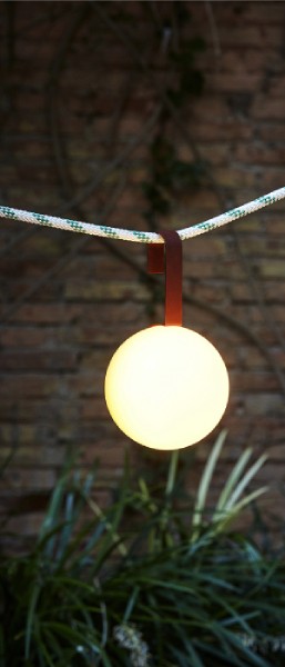 Circ M-3826X portable outdoor table light hangs from a line in a garden.