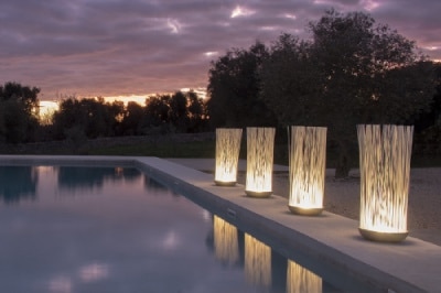 Don't Touch outdoor floor lights line the edge of an outdoor swimming pool at twilight.