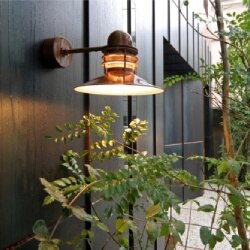 Nyhavn outdoor wall sconce from Louis Poulsen on a building exterior with rain coursing down the wall.