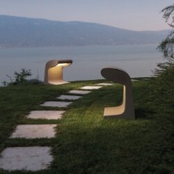 Borne Béton Grande outdoor floor bollard from Nemo lights a pathway on a hill overlooking a misty coastline.