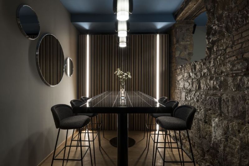 A luxurious contemporary dining room illuminated by a linear cluster of Manila T PE pendants, designed by Sebastian Herkner for Parachilna.