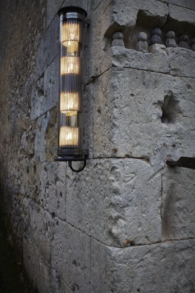 An in situ photo highlighting the contrast between In the Tube 120-700 outdoor wall light and a textured wall of stone blocks.