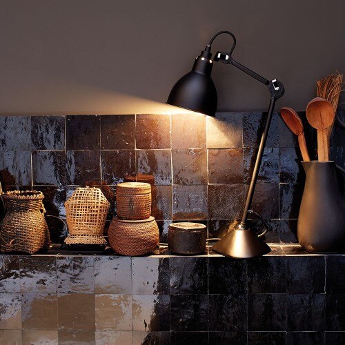 Bernard-Albin Gras' timeless Lampe Gras, now from DCWéditions, on a ledge in a kitchen of rustic tile.