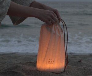 Uma table lamp from Pablo emits a soft glow through a decorative carrying bag.