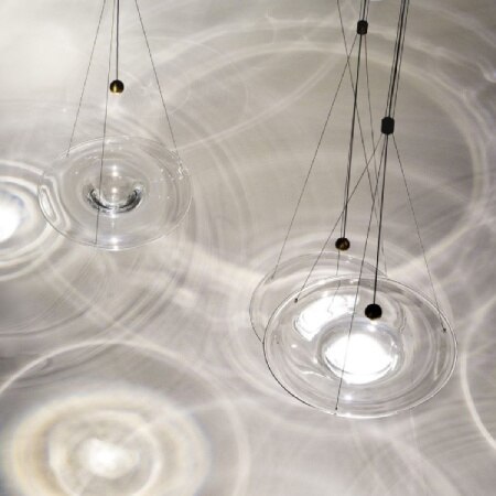 A cluster of Nao Tamura's Momento Lights from WonderGlass, viewed from above with the watery ripple shadow effect on the ground below.