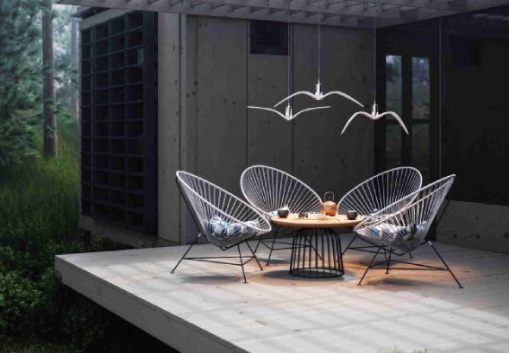 A trio of Boris Klimek's Night Birds pendants hang over a table and chairs on a contemporary patio.