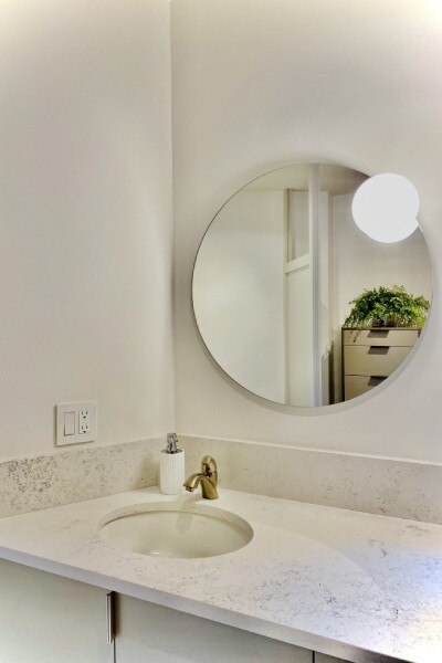 Estiluz's large Circ mirror, Circ A-3706-W wall mirror light hangs in a minimalist bathroom.