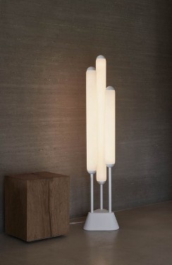 Lucie Koldova's Puro floor lamp, the latest addition to her cigar-inspired Puro collection of lights for Brokis, sits next to a side table in a living room.