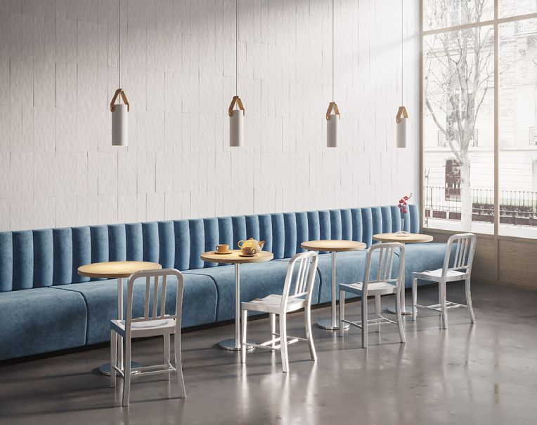 A linear cluster of Spero pendants from Cerno hangs above tables along the wall of a cozy cafe.