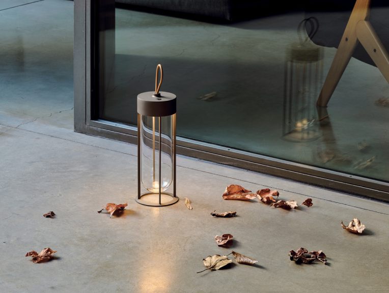 Philippe Starck's newest addition to his In Vitro collection for Flos, In Vitro Unplugged portable table light, sits on a patio amid a scattering of leaves