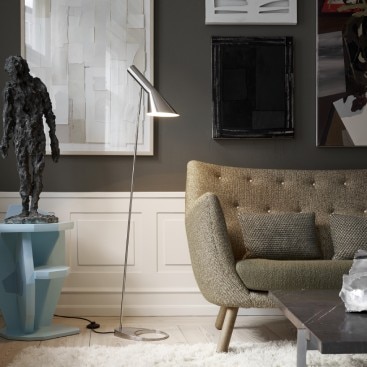 AJ floor light serves as a reading lamp next to a green mid-century modern couch in a contemporary living room.