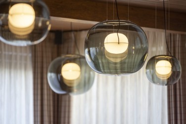 A close-up of Lucie Koldova's Big One pendants in front of some backlit curtains