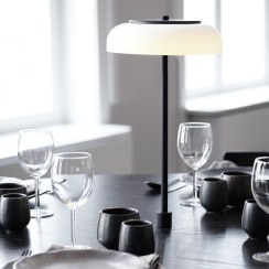 Blossi In-Set table light in black with a frosted diffuser, installed in the centre of a restaurant dining table.