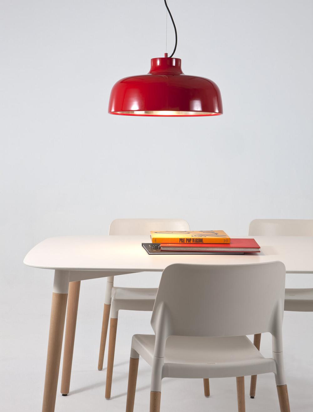 The M68 in polished aluminum (left) and vibrant red (right) are inspired by the female shoulders, designed in 1962 and edited by Santa & Cole in 1995.