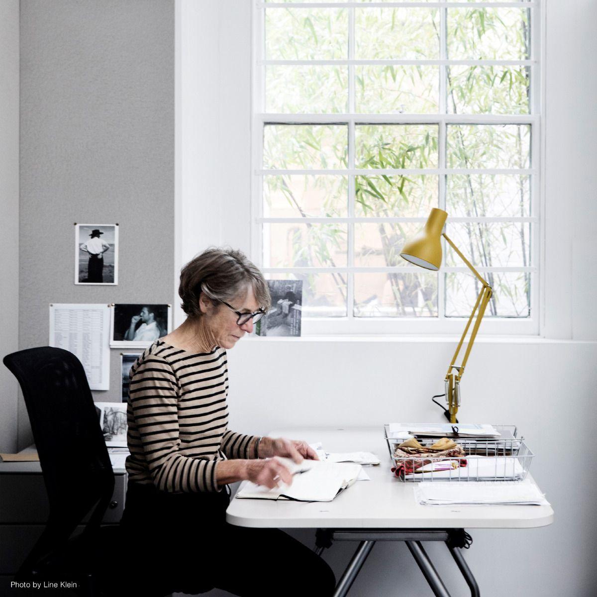 British fashion designer Margaret Howell working at her desk, illuminated by the special Margaret Howell Edition of the Type 75™ Desk Lamp in yellow ochre