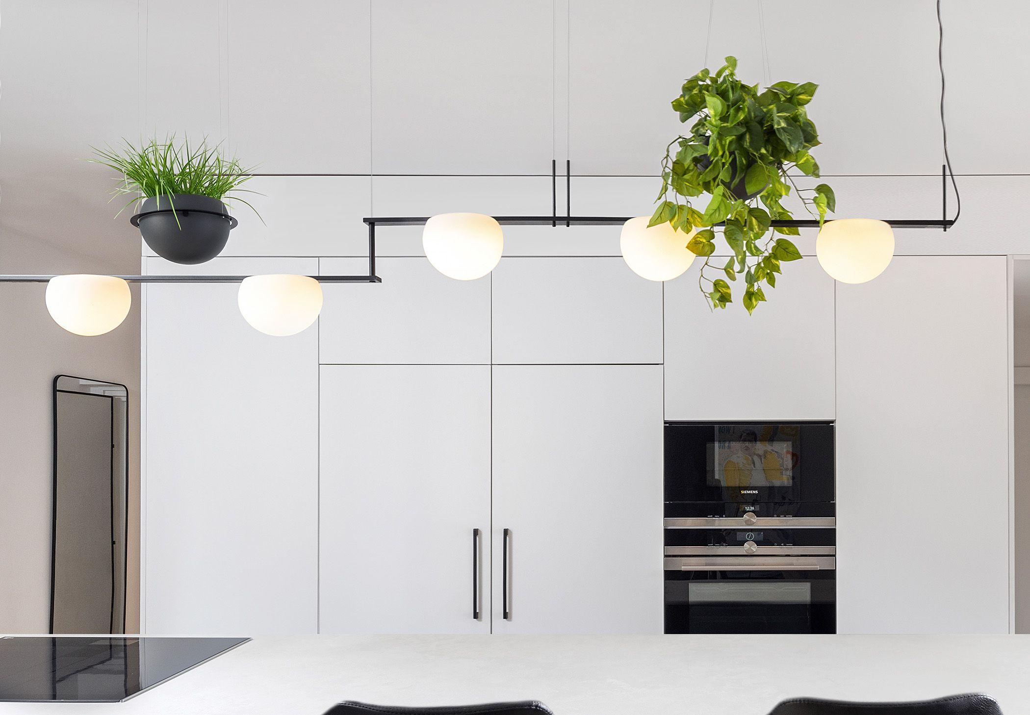 The Circ Suspension in a linear form with additional greenery and accessories lights and warms up a modern and minimalistic kitchen.