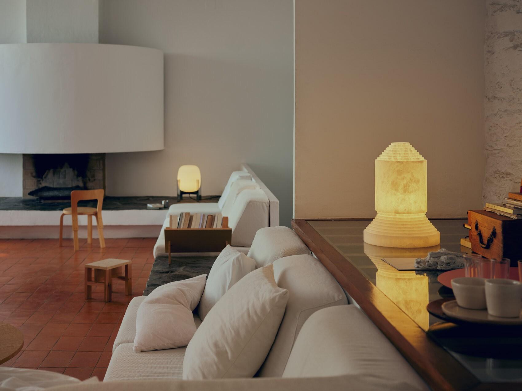 A serene and minimalist living space illuminated by the Cesta Metallica Table Lamp (left) and Babel Table Lamp (right) from Santa & Cole.