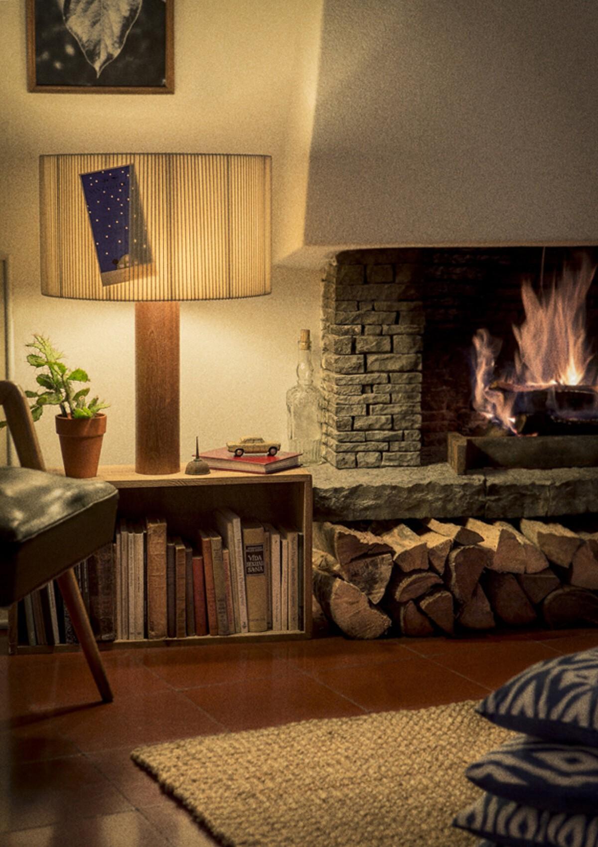 A cozy fireplace with books, art, and personal belongings lit by the Moragas Table Lamp from Santa & Cole (left). A large window with a generous ledge and personal items on display sit alongside a Lumiere XXL Table Lamp from Foscarini.
