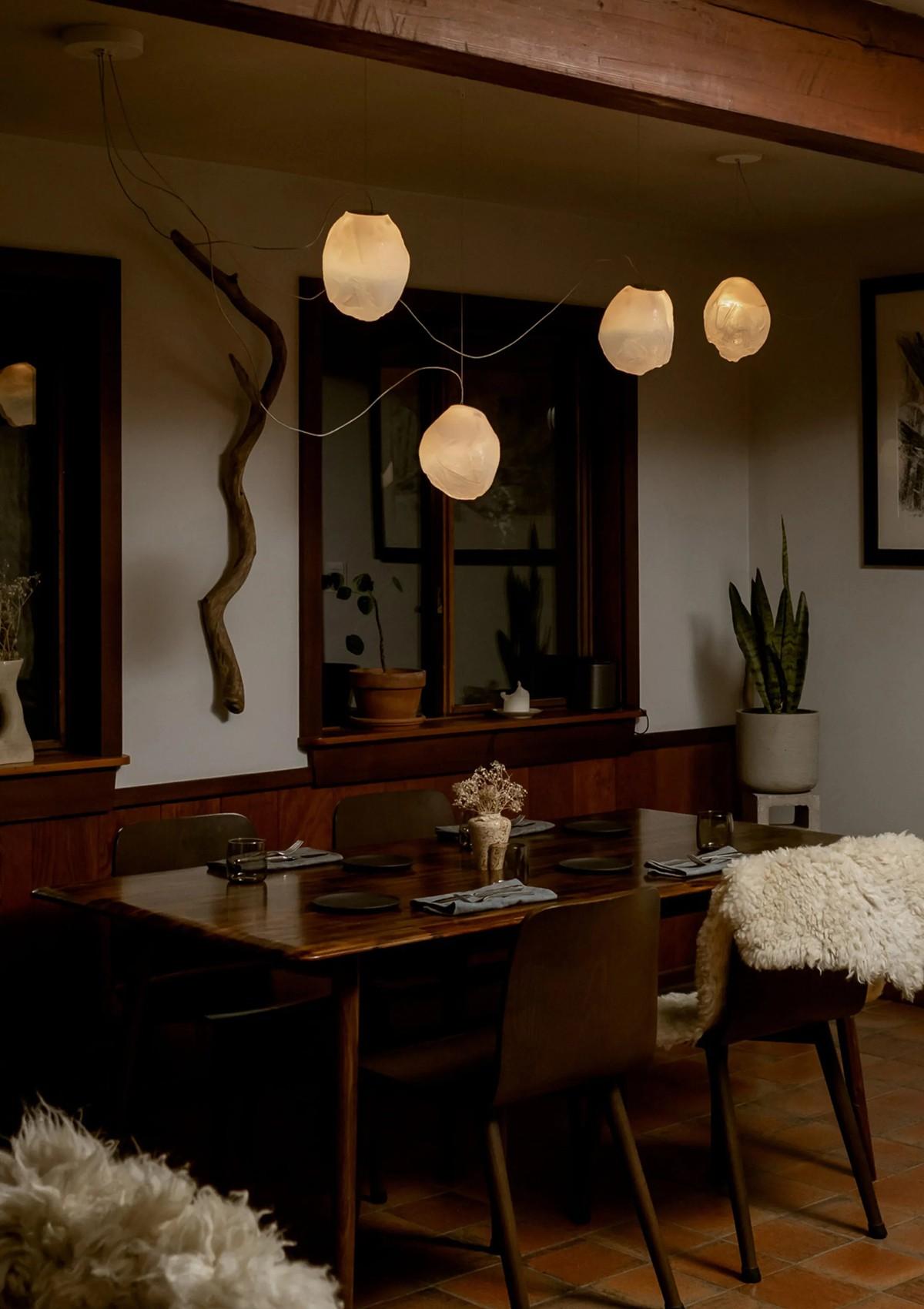 The 73 Series of Suspensions from Bocci (left) and the cluster of the Maija Suspensions from Santa & Cole (right) add a spotlight to the dining area, complementing each respective interior design and style.