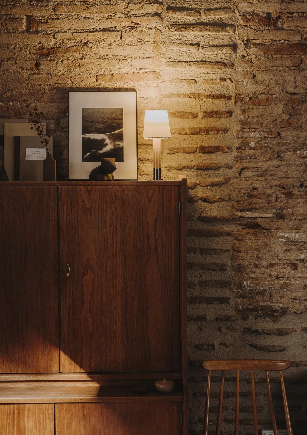 A reading nook defined by the Grashoppa Floor Lamp from Gubi (left); a hutch with photographs and personal items on display at the top with the Basica Minima Table Lamp from Santa & Cole (right)
